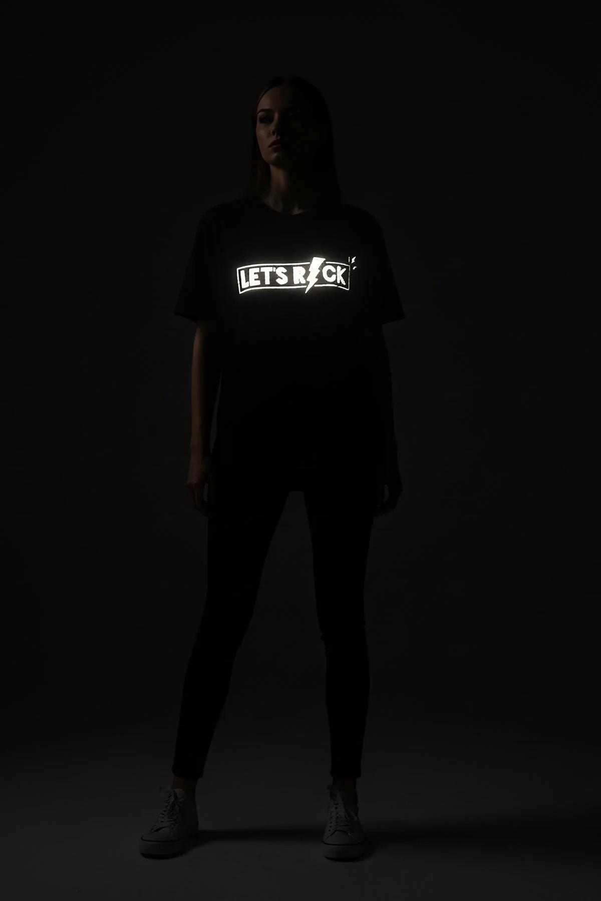 LET'S ROCK reflektör baskılı siyah tişört model üzerinde tam boy görünüm, oturur pozisyon