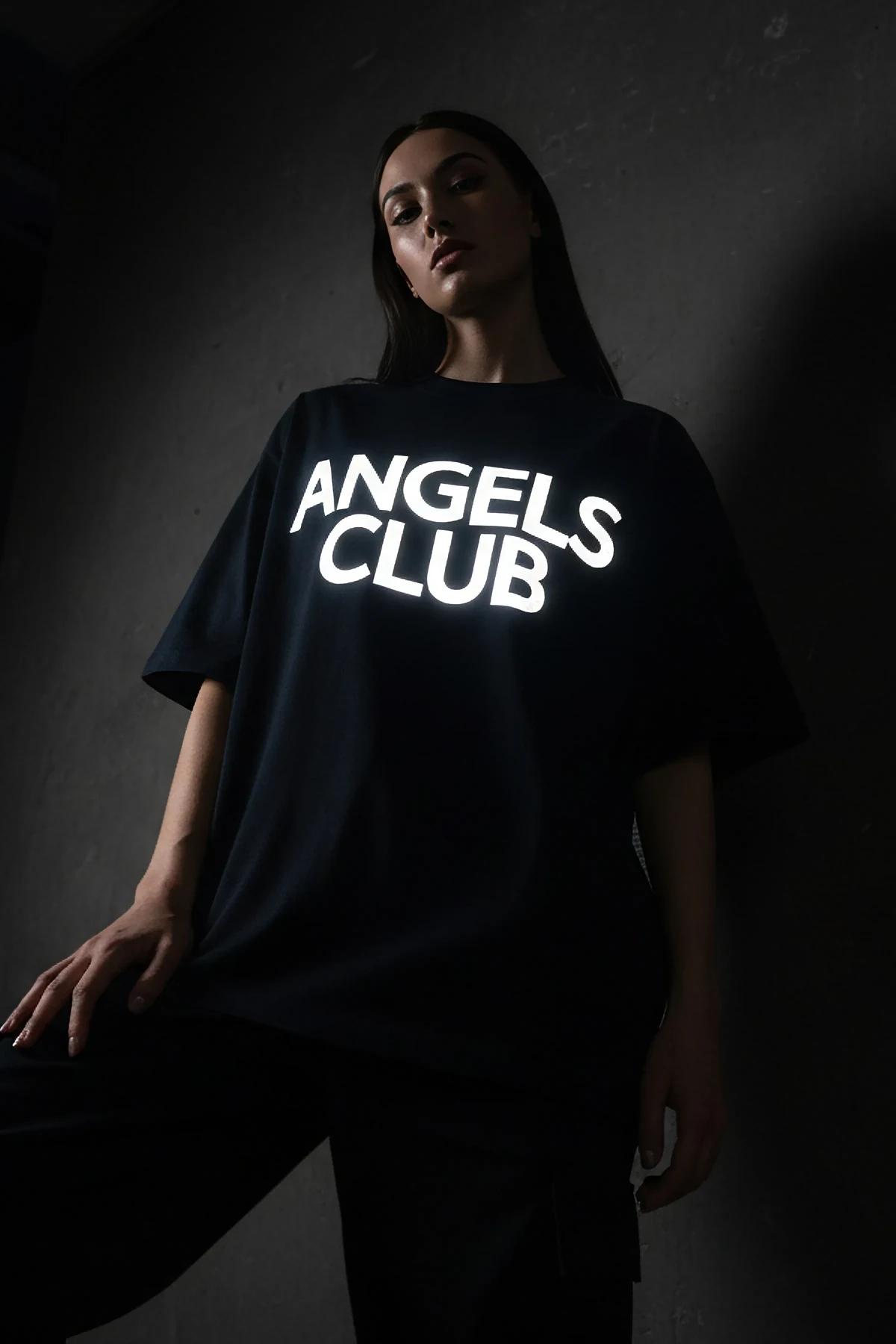 ANGELS CLUB büyük ön baskılı reflektörlü siyah oversize tişört kadın model üzerinde parlayan yazı