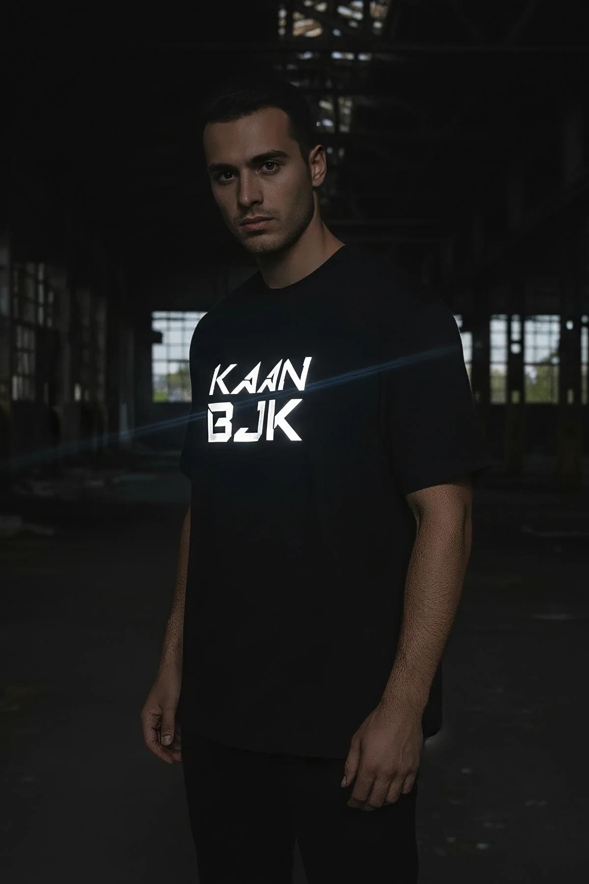 KAAN BJK tişört — model ayakta, yan reflektör şerit detayı ve parlayan baskı