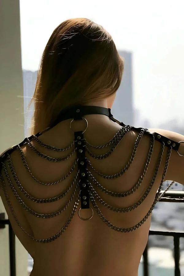Black faux leather layered chain body harness with choker neck, eight silver curb chains draped across bare back, back view